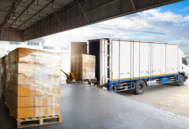 Open warehouse loading dock with pallets and trucks symbolizing fast fulfillment and delivery reliability.